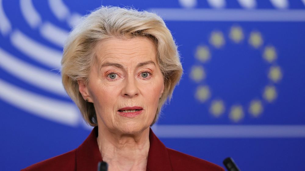 Ursula von der Leyen speaks at a podium with the European Union flag in the background.