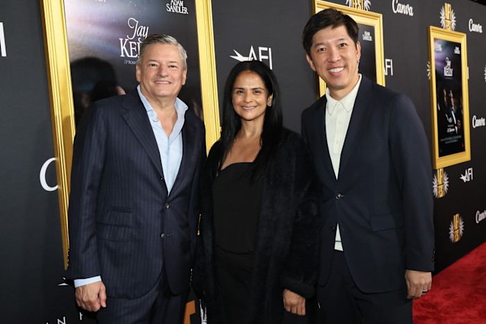 Ted Sarandos, Bela Bajaria and Dan Lin pose together on the red carpet at the “Jay Kelly” premiere during AFI FEST 2025.